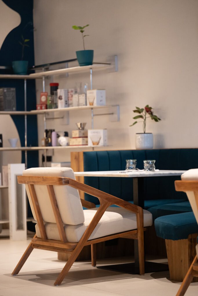 Wooden armchairs and teal velvet booth seating at Overflow Coffee, an aesthetic cafe in Golf City Lucknow