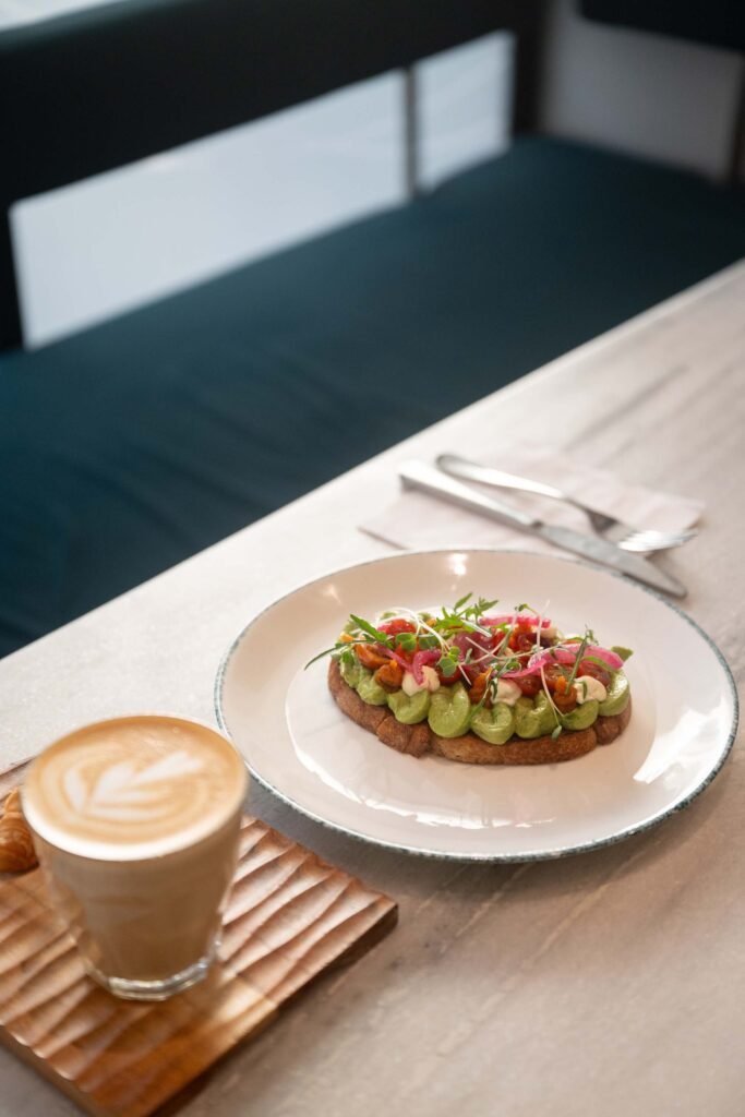 Avocado toast on sourdough with pickled onions, cherry tomatoes, whipped feta and microgreens served with a latte at Overflow Coffee, Golf City Lucknow