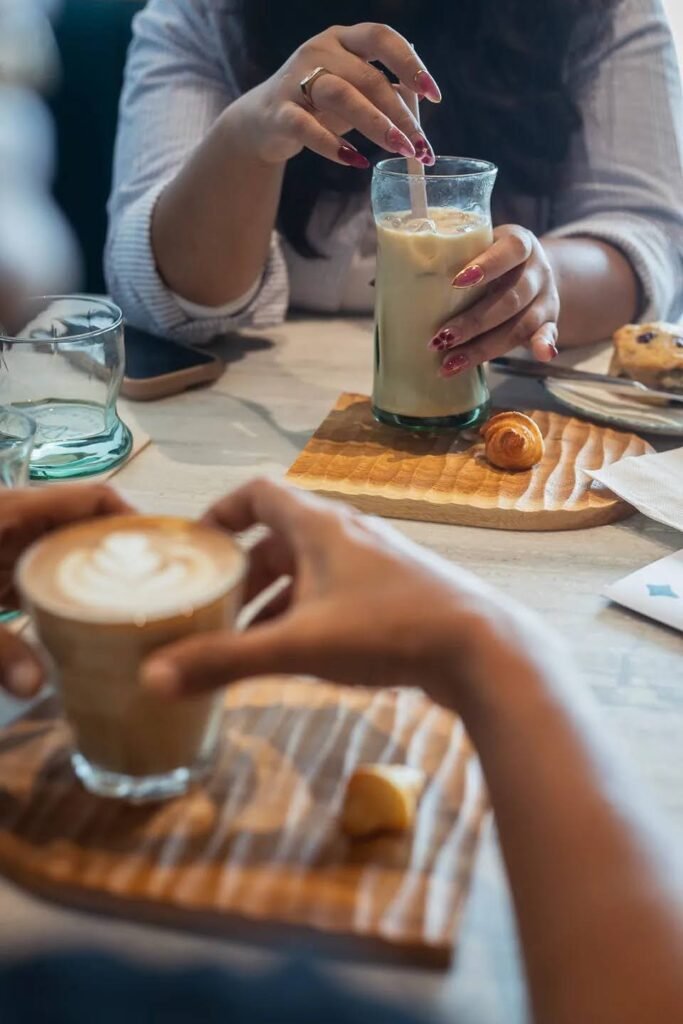 Two people sharing an iced latte and a hot latte with pastries at Overflow Coffee, a specialty cafe in Golf City Lucknow