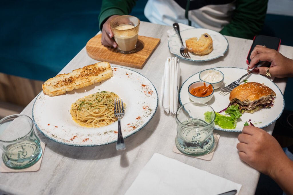 Lunch spread at Overflow Coffee Lucknow with Aglio e Olio pasta, smash burger, garlic bread and latte